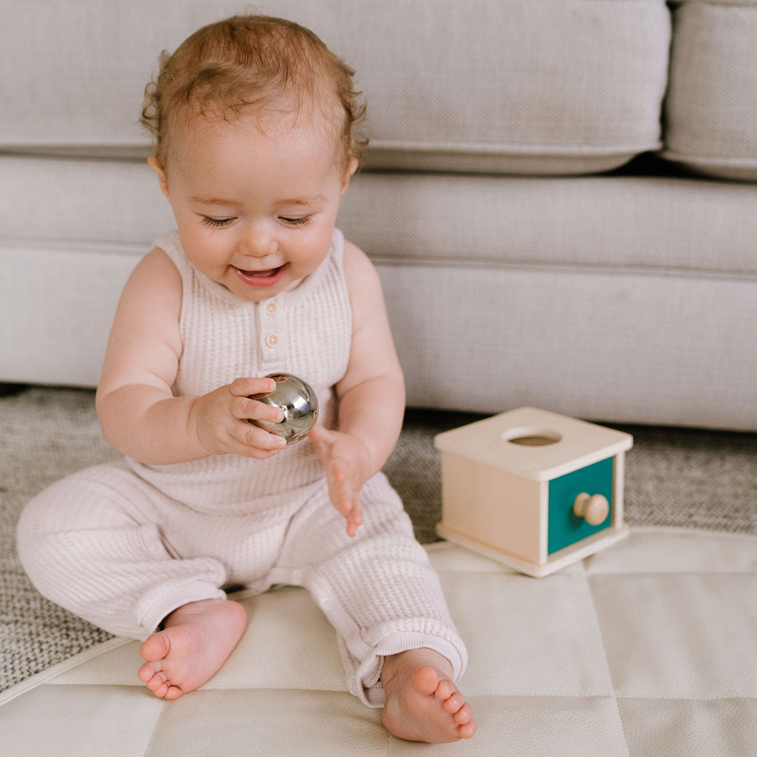 Wooden box and ball drop toy to teach object permanence.